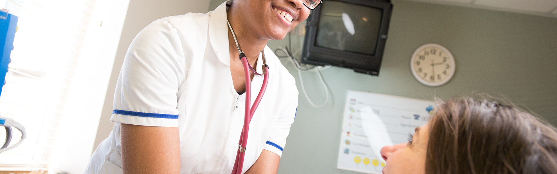 Georgia Piedmont Technical College nursing student smiles while examining a patient’s neck in a simulated clinical setting.